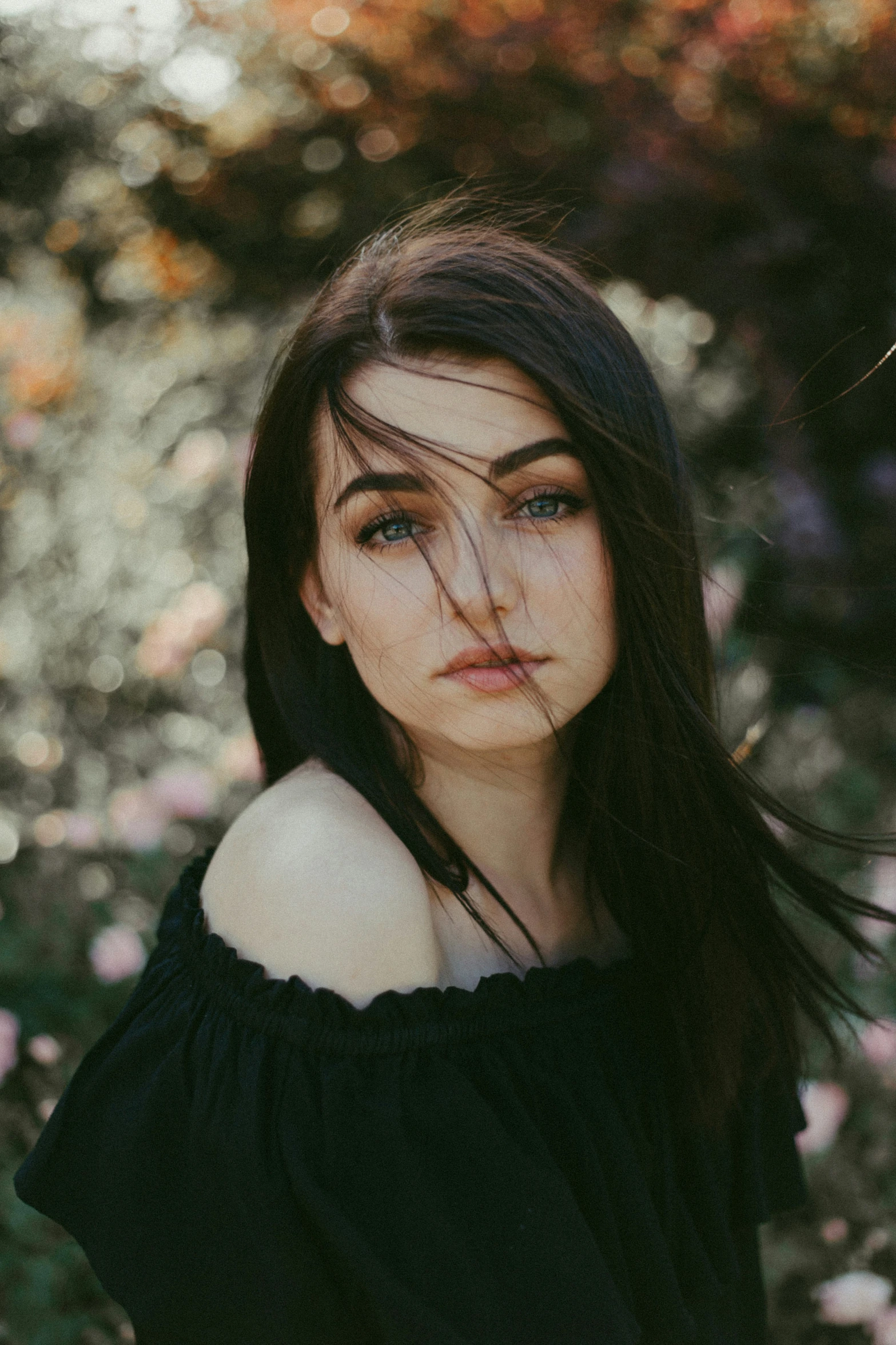 a young woman poses for a picture near some flowers