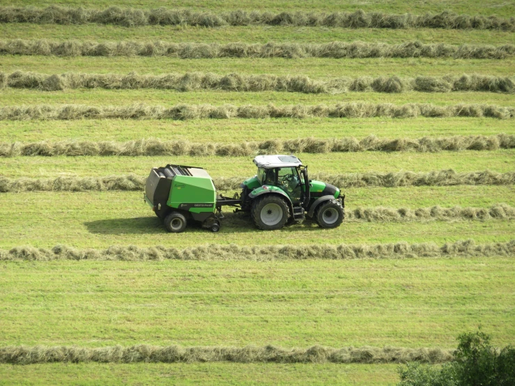 a tractor drives in a field with bales on it