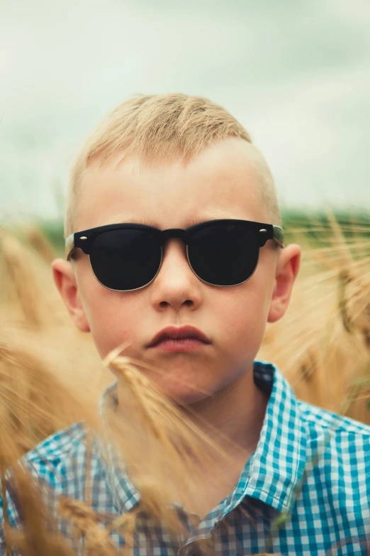 a little boy with some black glasses in a field