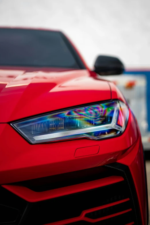 a close - up of a red sports car with the headlights of another car