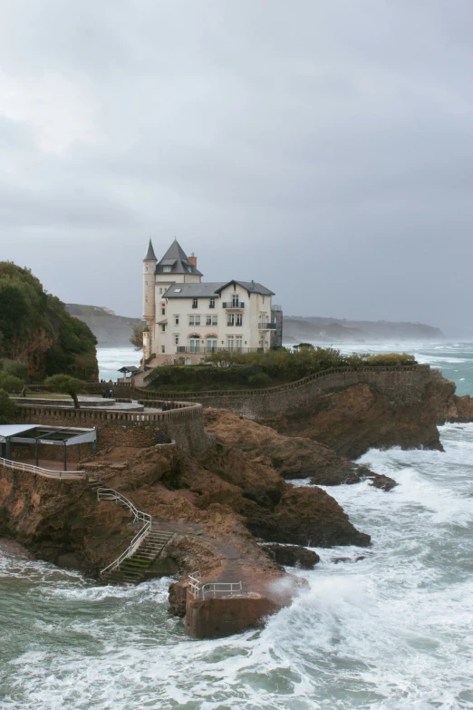 a house sitting on top of a rocky cliff near the ocean