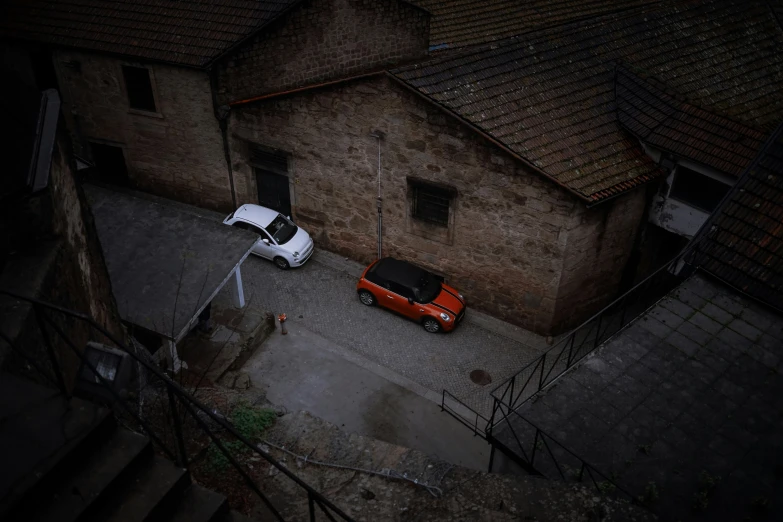 an orange car is parked in the street next to a small building