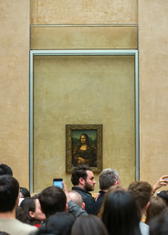 crowd watching a painting being displayed on a large wall