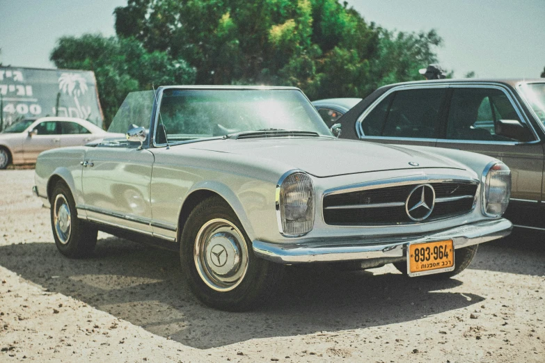 an older model mercedes benz is in front of another model car