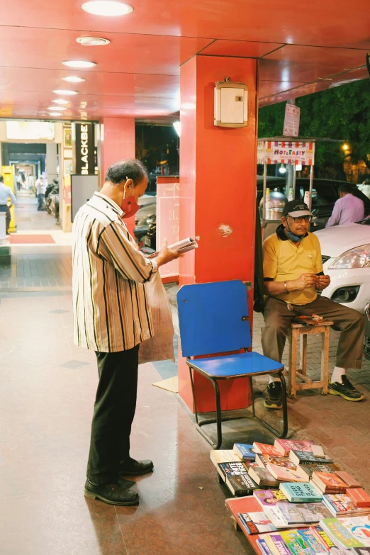 a man standing at a sidewalk with a bunch of folded books