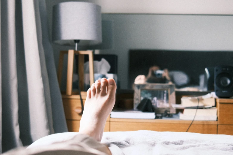 a person's feet on a bed next to a dresser