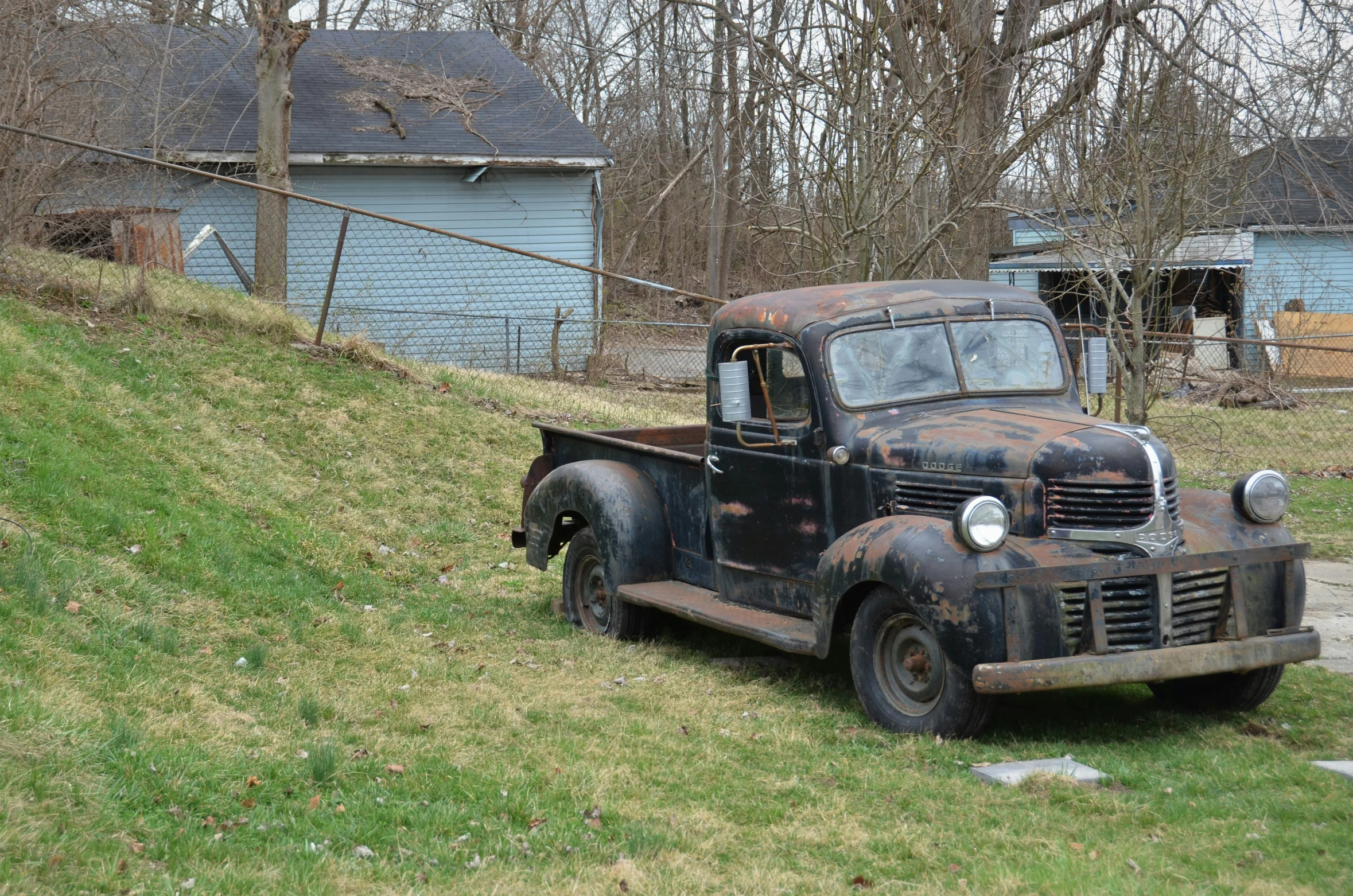 an old truck is parked on the side of a grassy hill