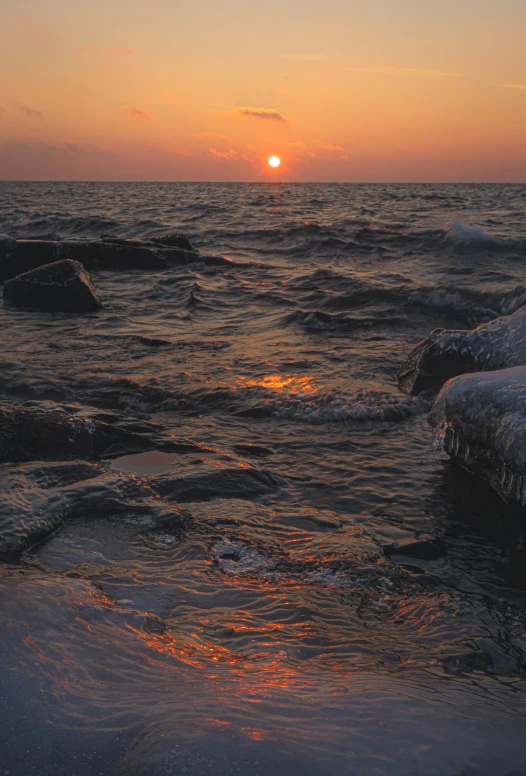 the sun is setting over the water and rock formations