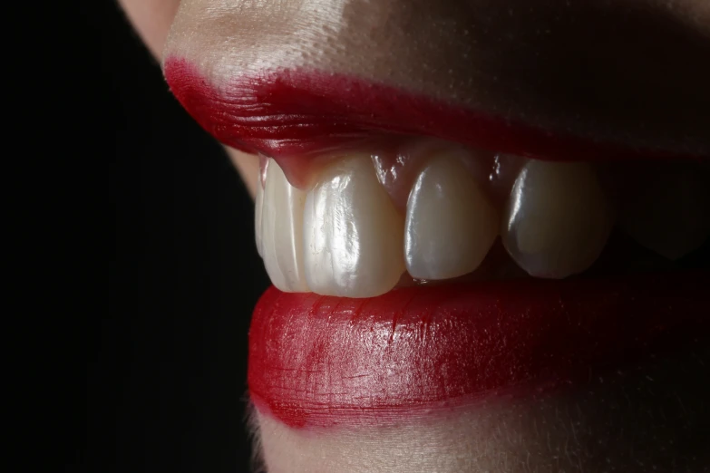 a woman with red lips is smiling and has white teeth