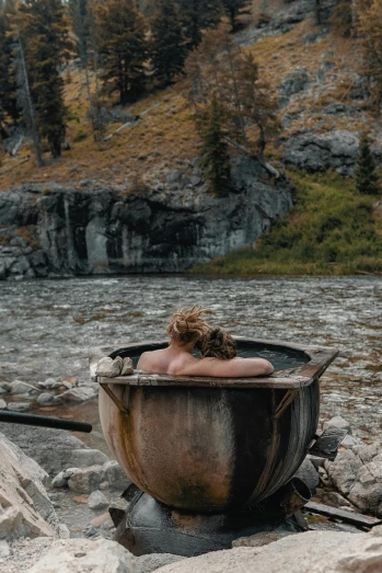 woman swimming in a bath tub outside by a mountain stream
