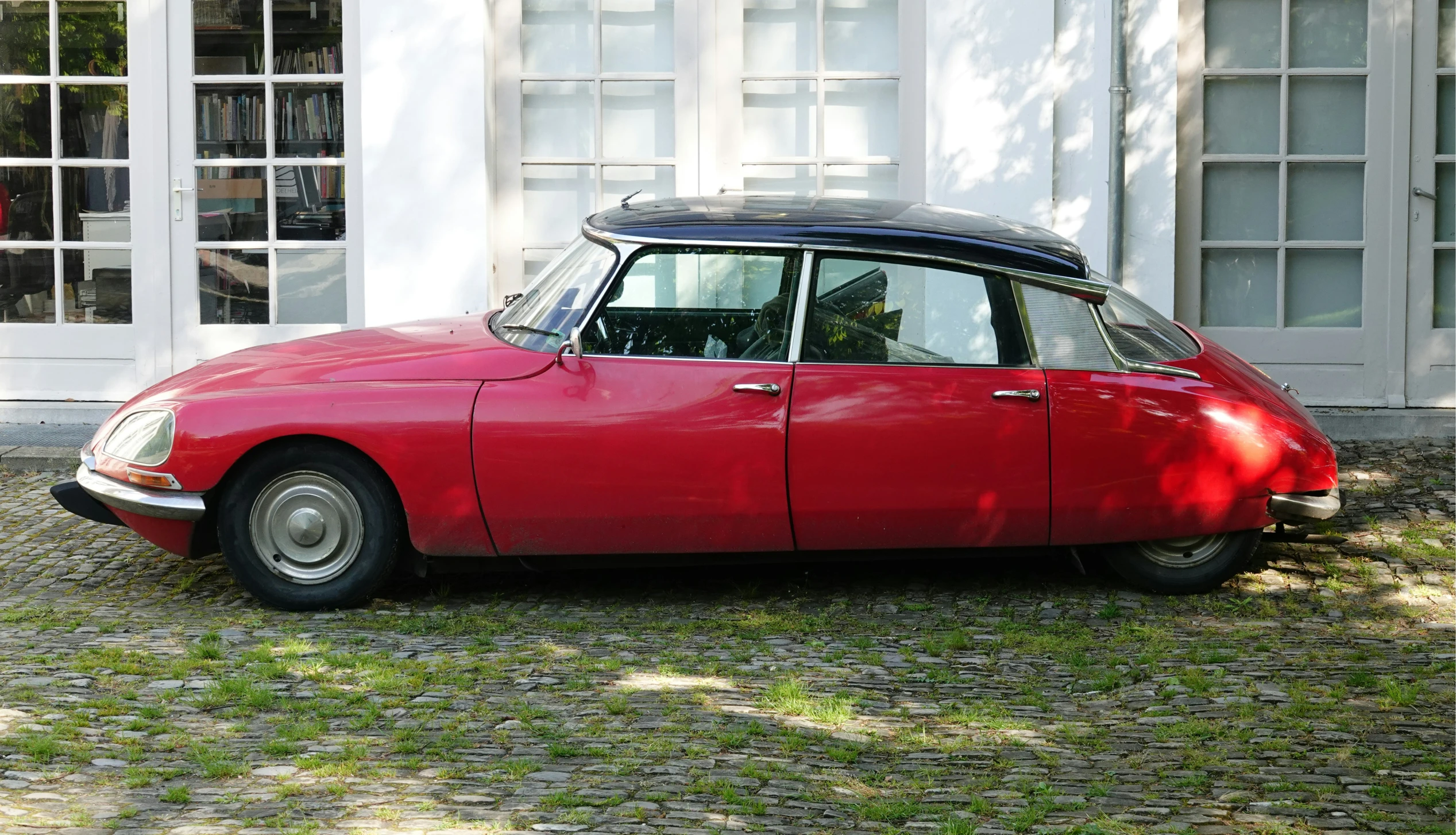 a red sports car parked in front of a white house