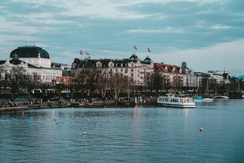 boats are on the river and many buildings line the shoreline