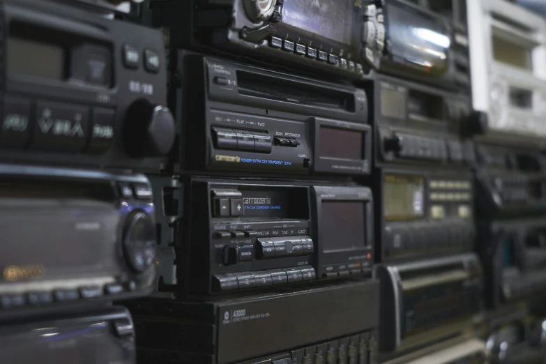 there are many old radio's stacked high on the wall