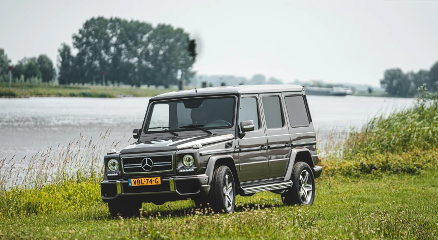 a car is parked in the grass next to the water