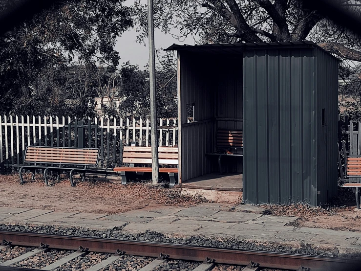 two wooden benches on train tracks near a structure