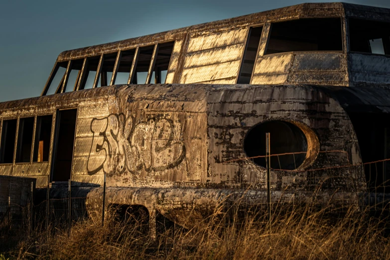 a dirty bus that has been sitting by a fence