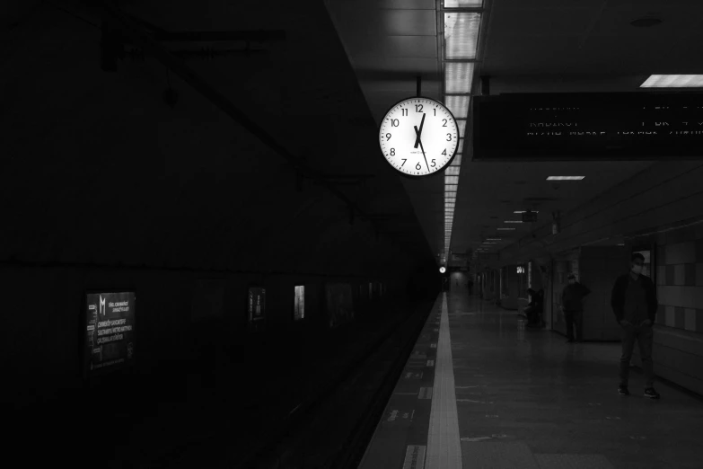 black and white pograph of a clock at the end of a train station