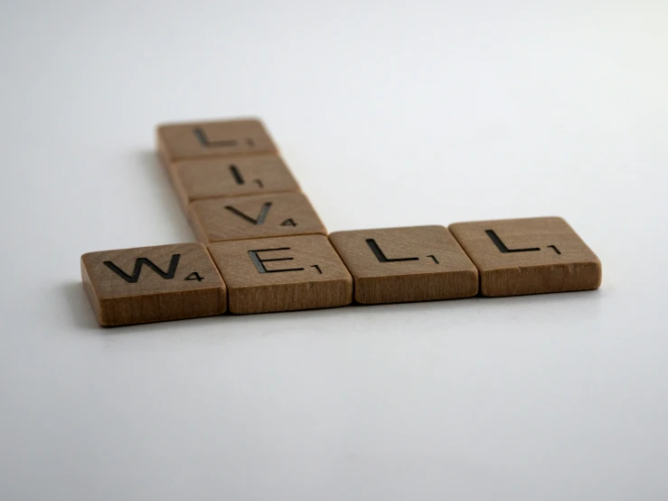 a scrabble - letter spelling set with wooden letters saying live well