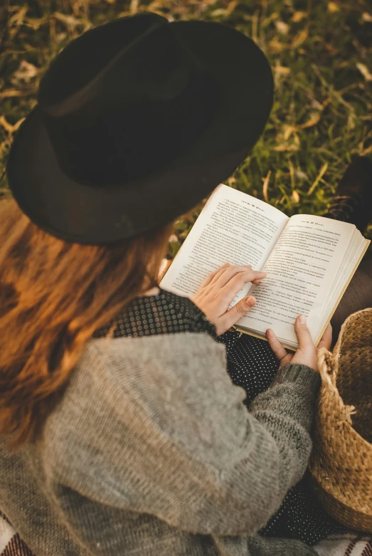 a woman sitting on the grass reading a book