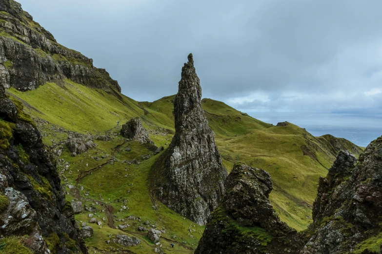 a large green mountain is surrounded by tall rocks