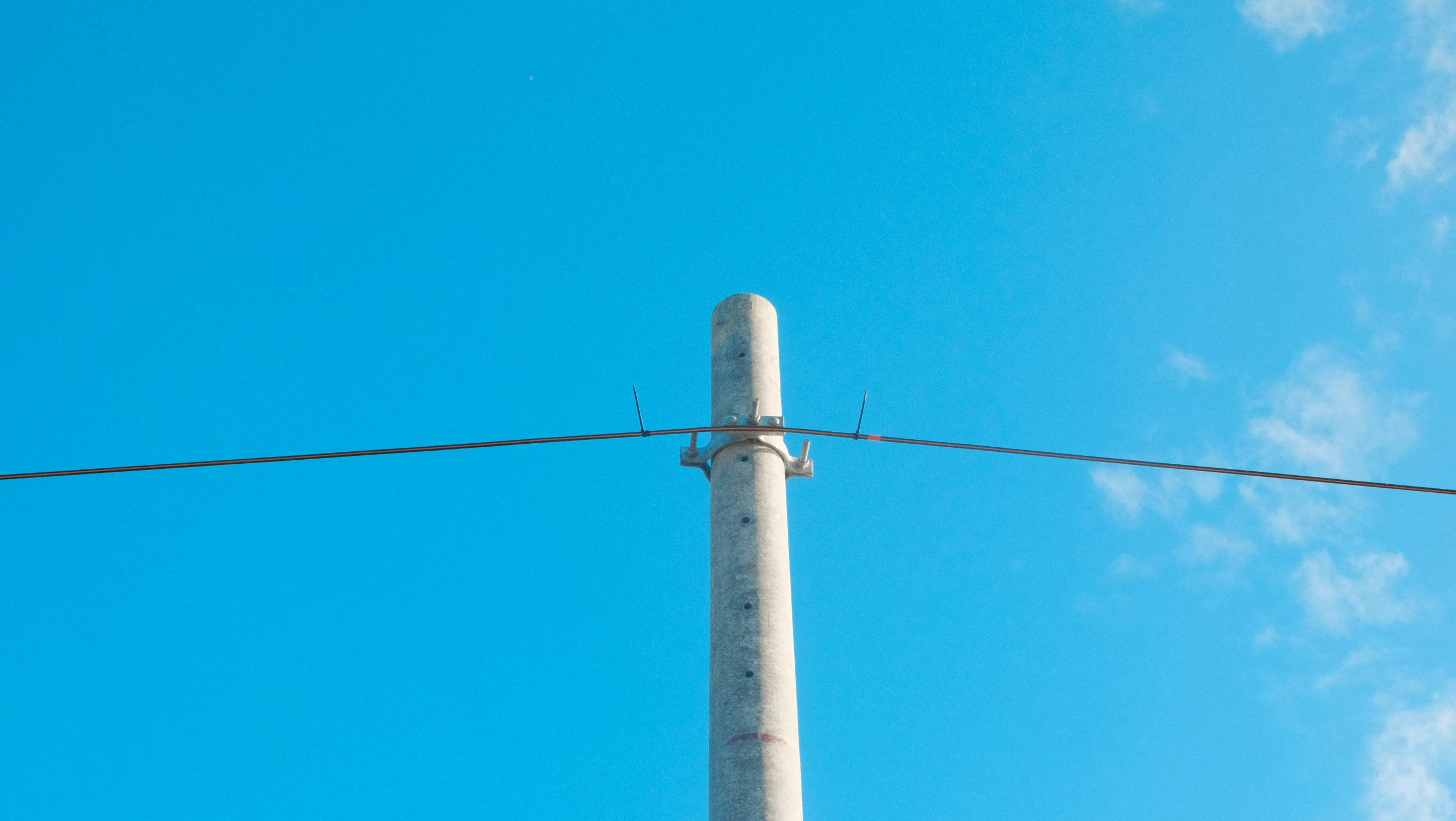 a large metal pole and electrical wires under a blue sky