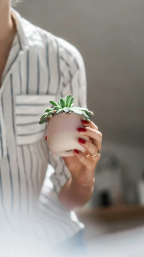 woman holding a pot with greenery growing out of it