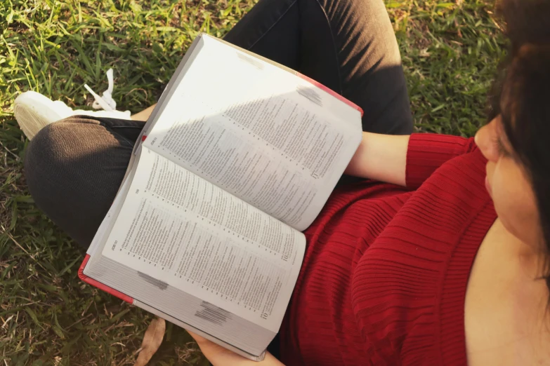 a woman reads a book on the grass