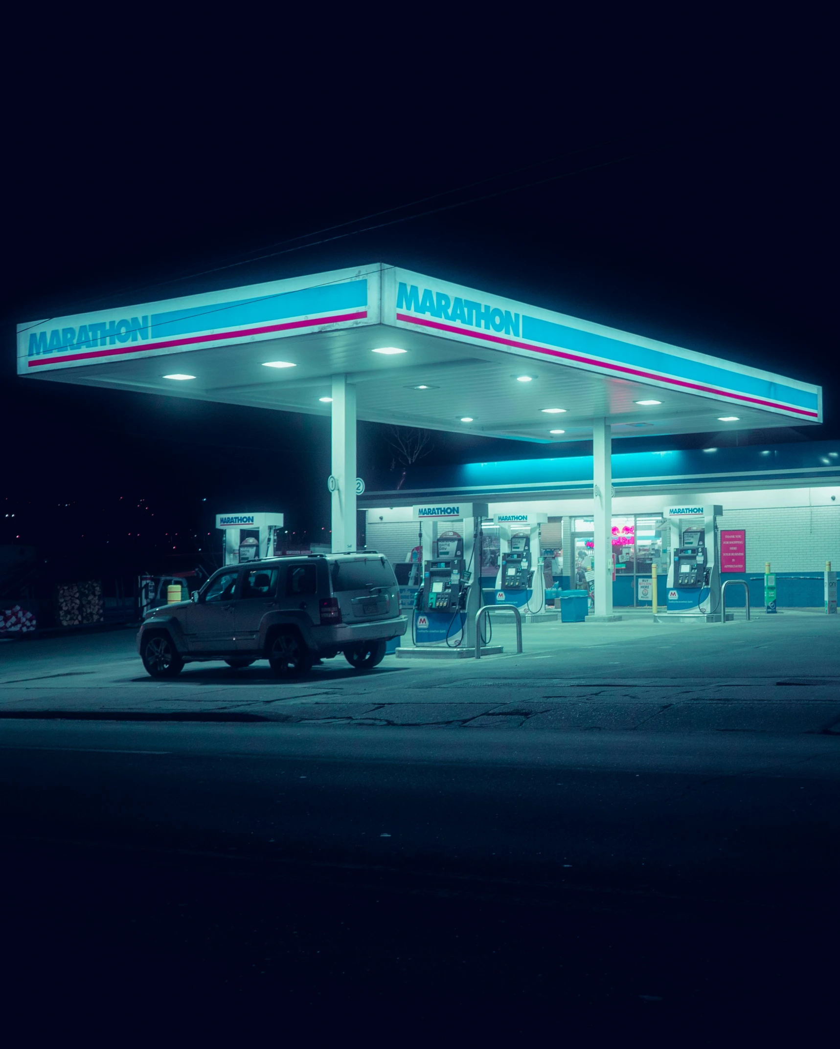 a dark parking lot with the service station lit up