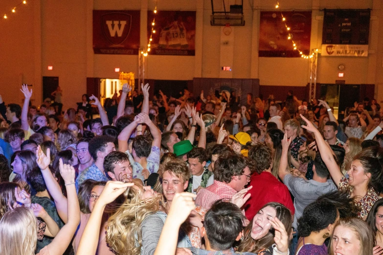 a large group of people dancing with their hands up