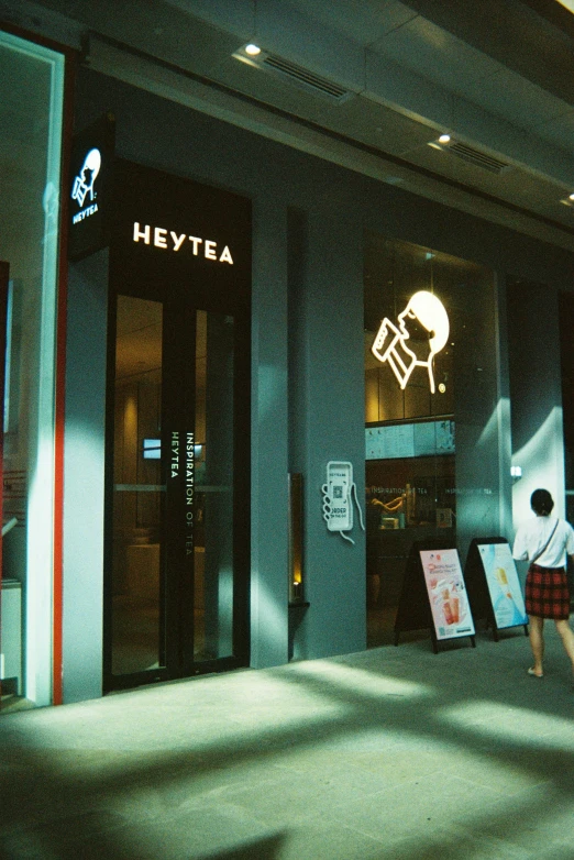 people walk by a building that is displaying a heve tea logo