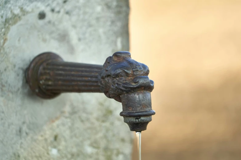 an old water faucet in front of a gray wall