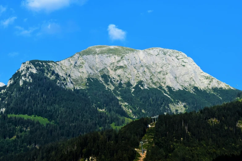 a large mountain range with trees on it and a sky background