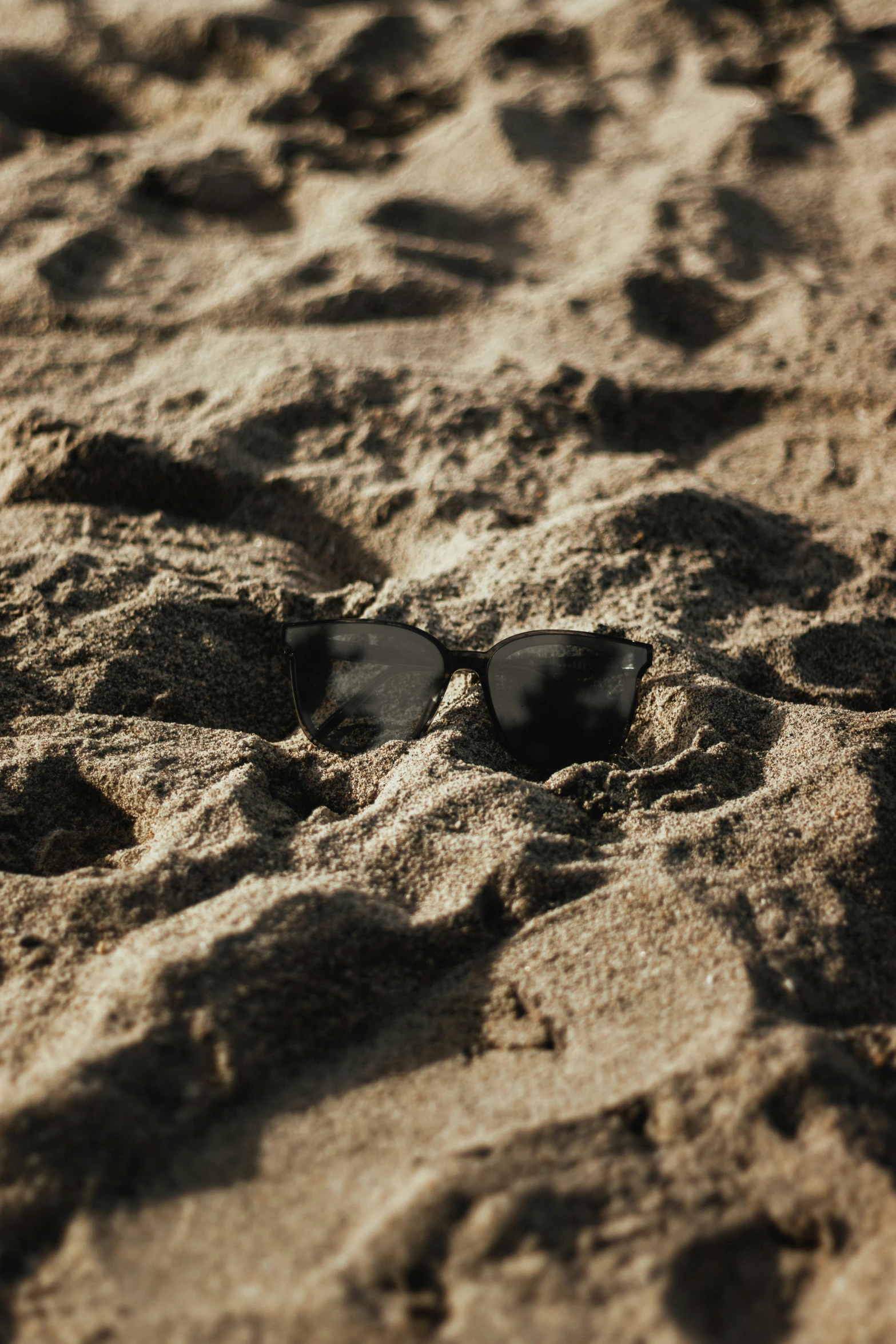 two glasses laying in the sand on the beach