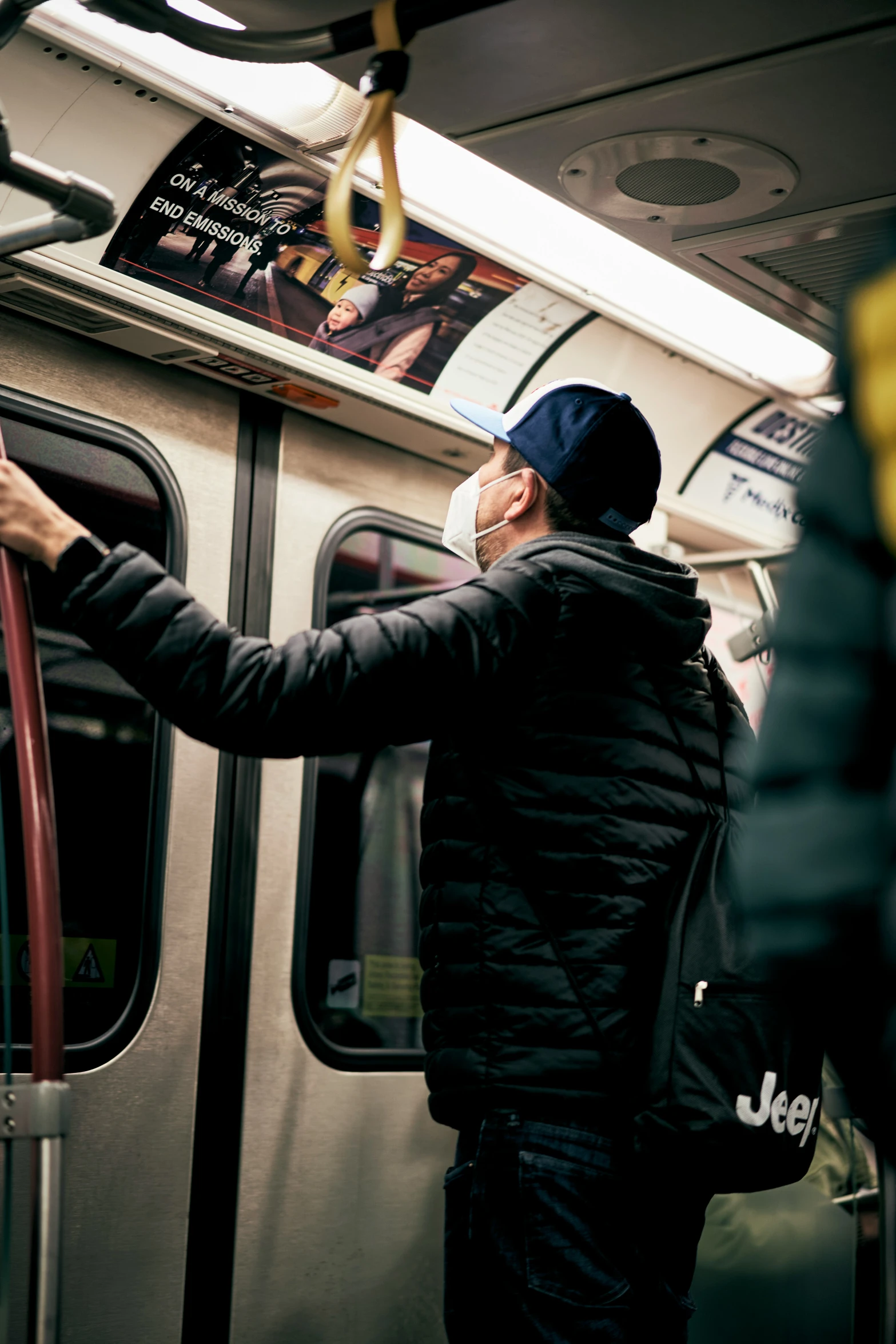 a man in a cap and black jacket standing on the subway