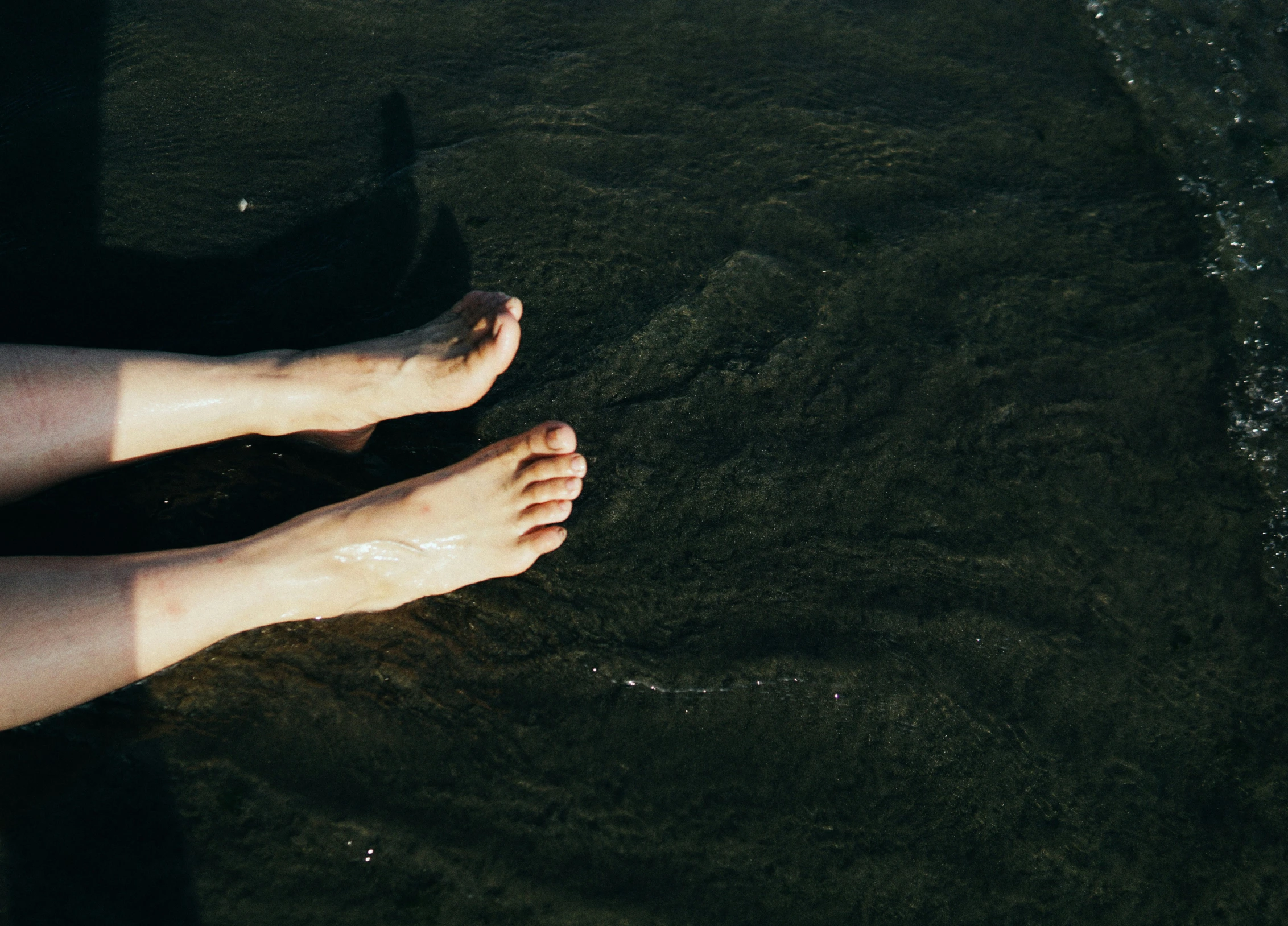 a bare foot on a black surface in the sun