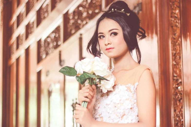  in an elegant dress holding a white flower