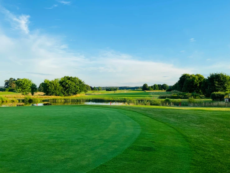 an empty golf course with a pond and some trees