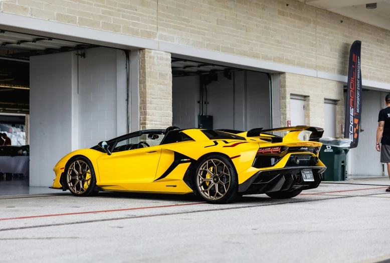 a person standing next to a large yellow sports car