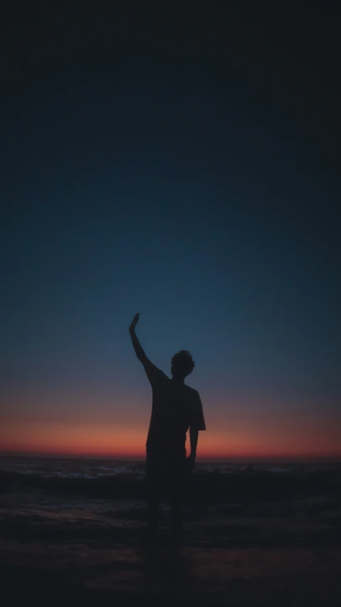 man standing in water at twilight throwing a frisbee