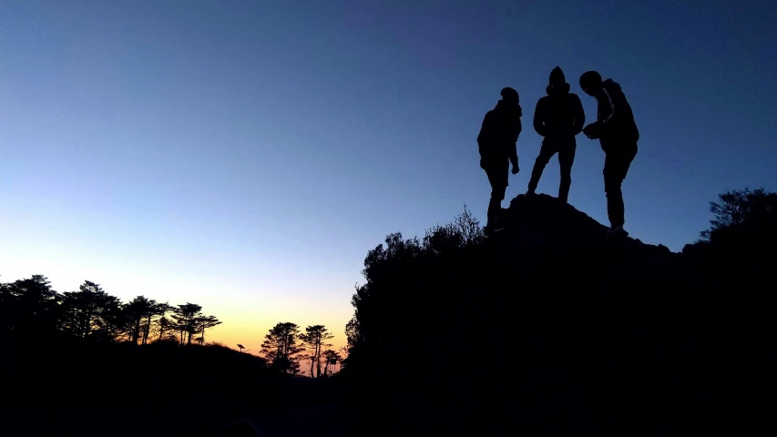 the silhouettes of three people on top of a mountain