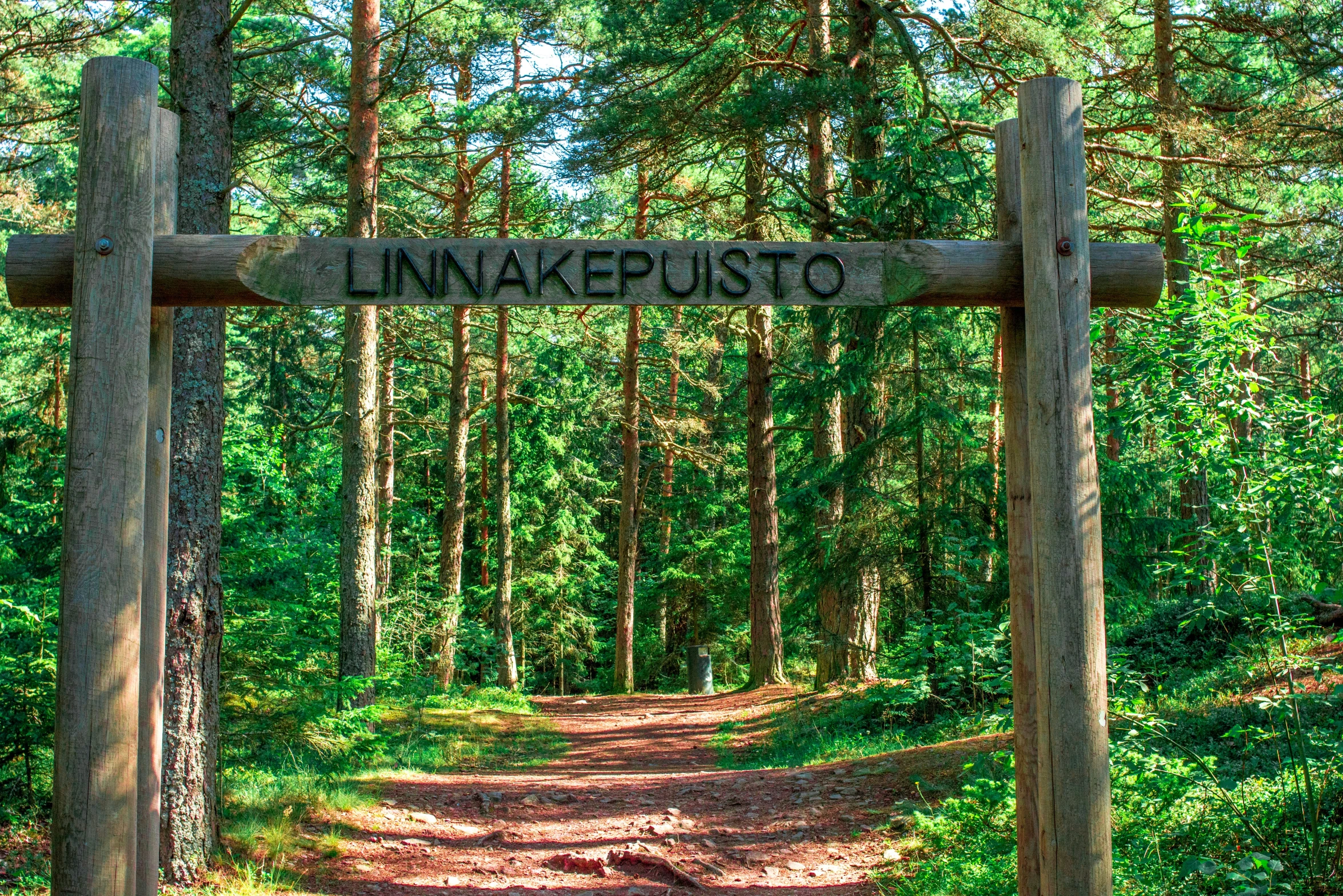 an exit into an area covered in trees with a sign on it that says inakepisto