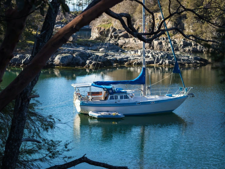 a white boat floating down a river next to rocks