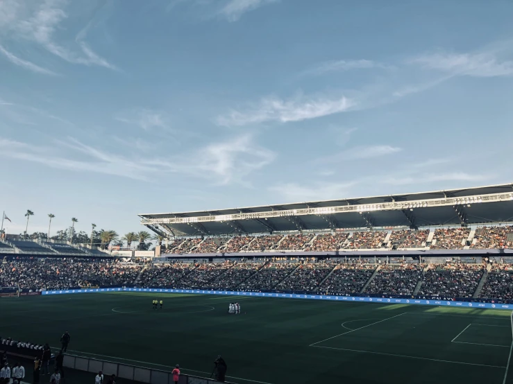 a field full of people standing in front of a stadium