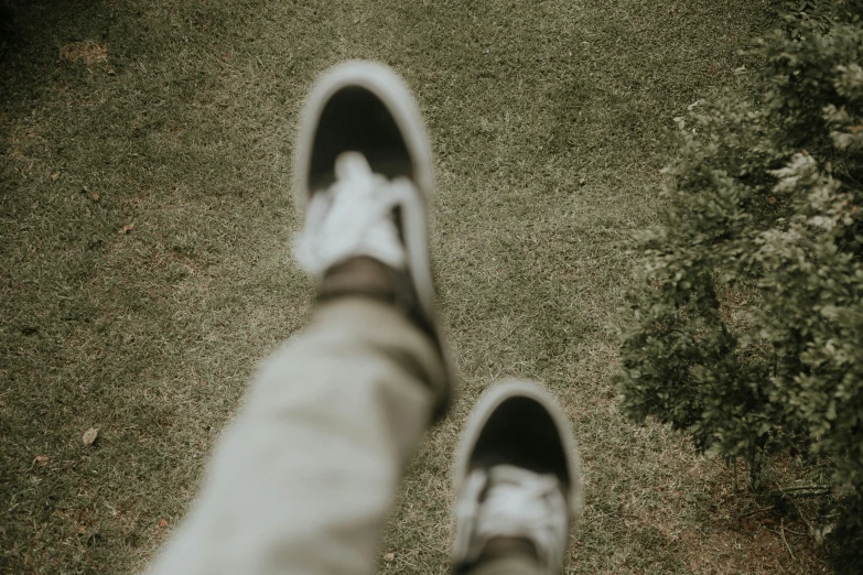 feet in shoes walking across the lawn in black and white