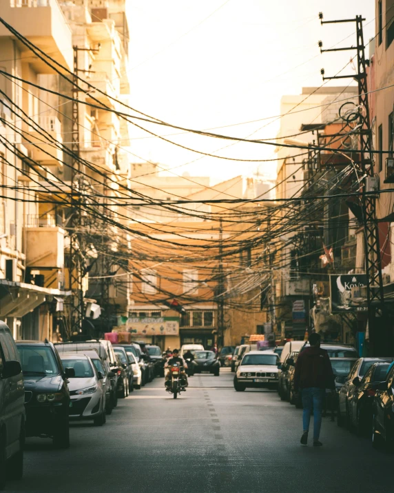 a person walking down a street with lots of power lines above