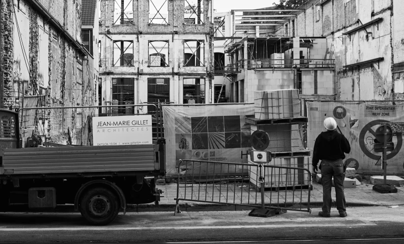 a truck and a person standing on the sidewalk near some buildings