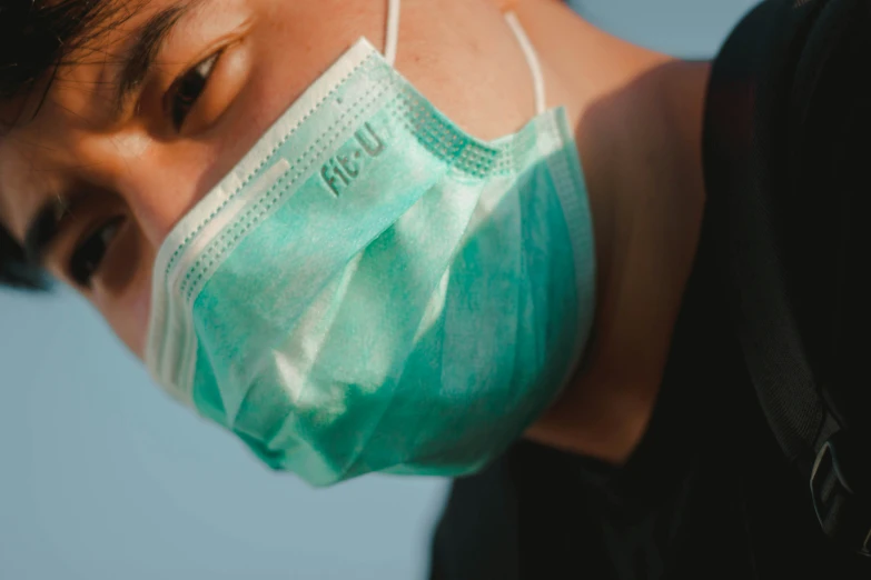 a woman wearing a face mask standing against a blue sky