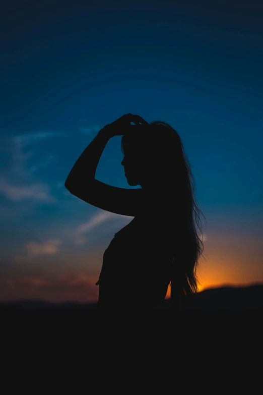 a girl standing in front of the sun wearing long hair