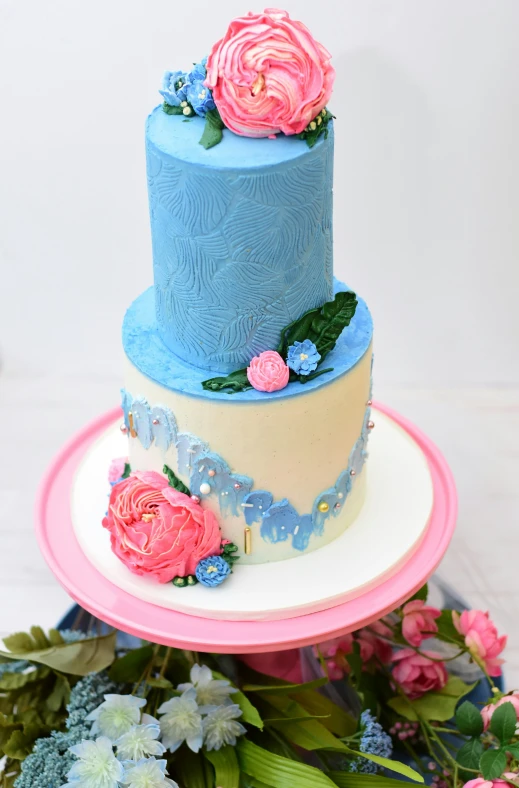 three tier blue and pink cake with flowers on each layer