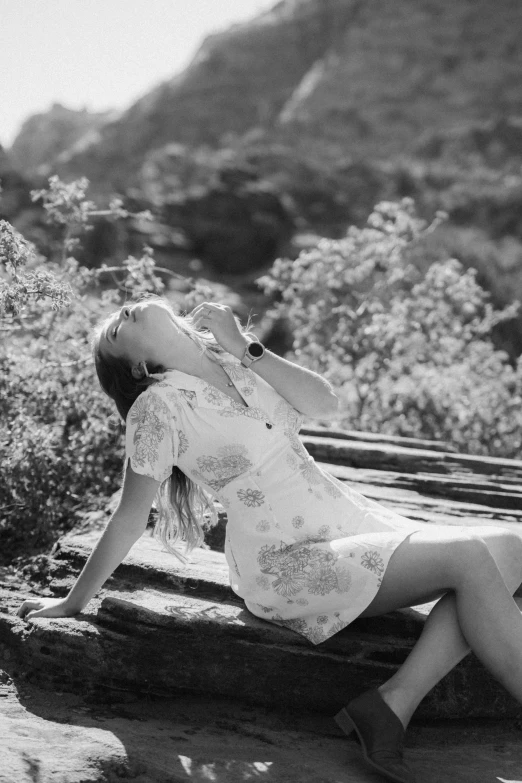 a girl laying down in front of a tree and mountain